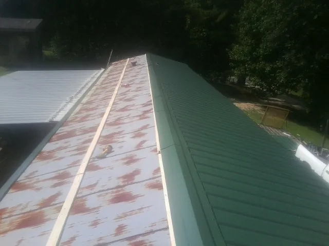Old rusted panels beside newly installed green metal roofing — Wind Damage Roof Repair by Roofing Brothers in Sunset Beach