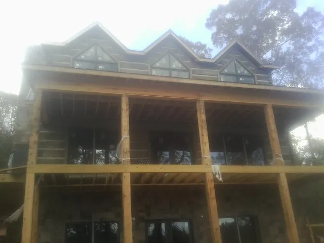 Dormers and porch framing on a large log home under construction — Roof Coating work by our crew in Sunset Beach